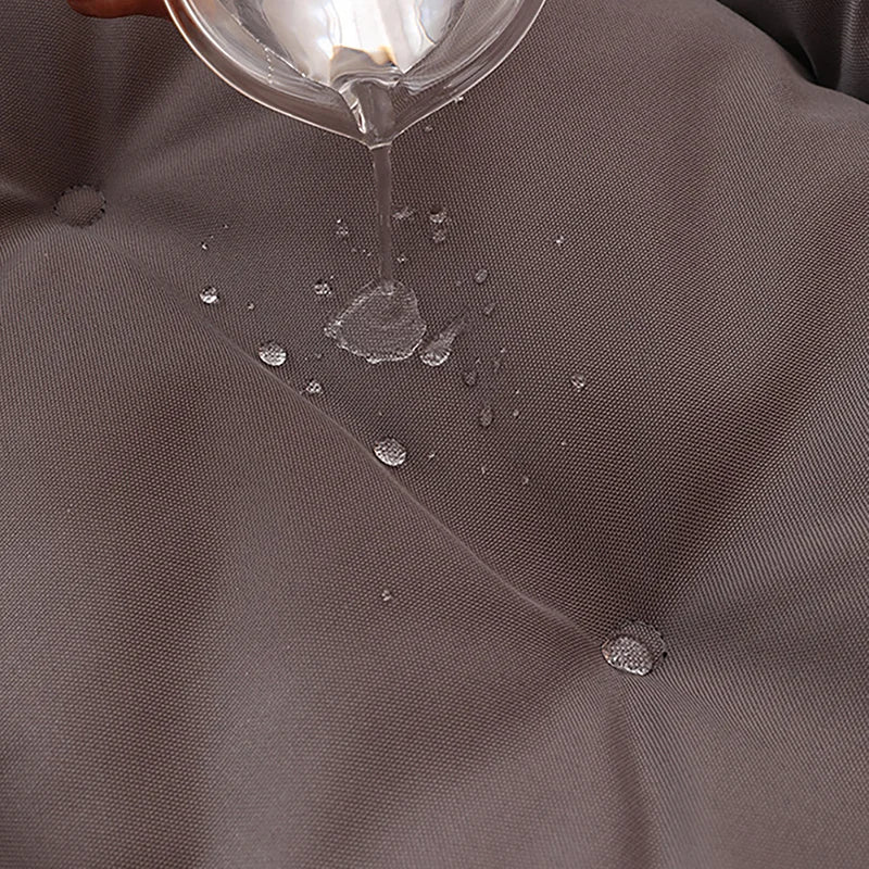 Close-up of grey 600D Oxford waterproof dog bed fabric with water being poured onto the surface.