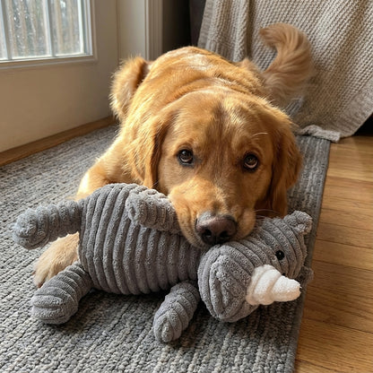 Dog lying on a carpet with a gray elephant plush toy