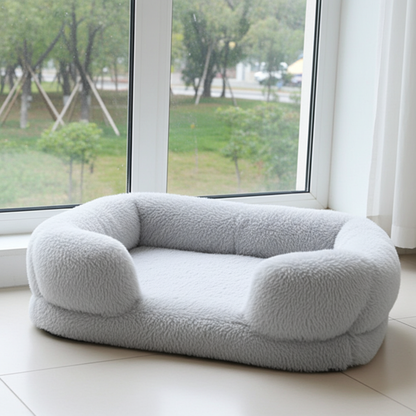 Gray pet bed on a white floor with a large window in the background