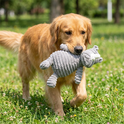 Dog playing with a gray plush toy in a grassy park