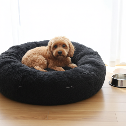 Dog lying on a dark gray fluffy pet bed in a room with a light wooden floor.