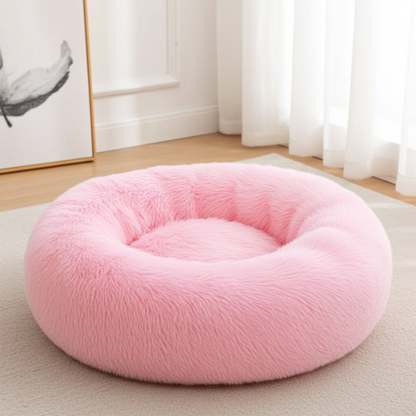 Pink donut pet bed on a light-colored floor with a neutral background