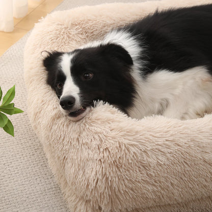 Black and white dog lying on a fluffy beige pet bed.